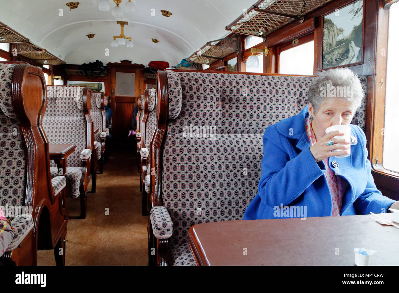 Une femme plus âgée de boire le thé sur le train à vapeur sur rail pointe de Bakewell, Derbyshire Banque D'Images