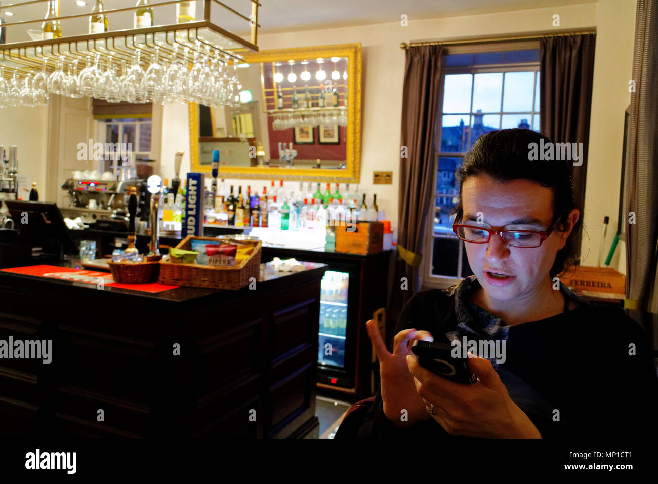 Une jeune femme obtenir de bonnes nouvelles sur son iphone dans le bar de la Rutland Arms de Bakewell, Angleterre Banque D'Images