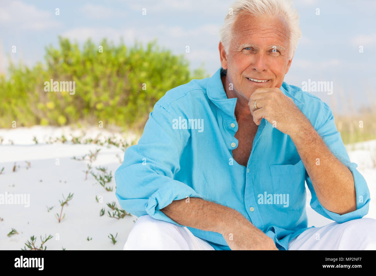 Portrait of a happy handsome man attrayant de s'asseoir à l'extérieur, sur une plage et smiling Banque D'Images
