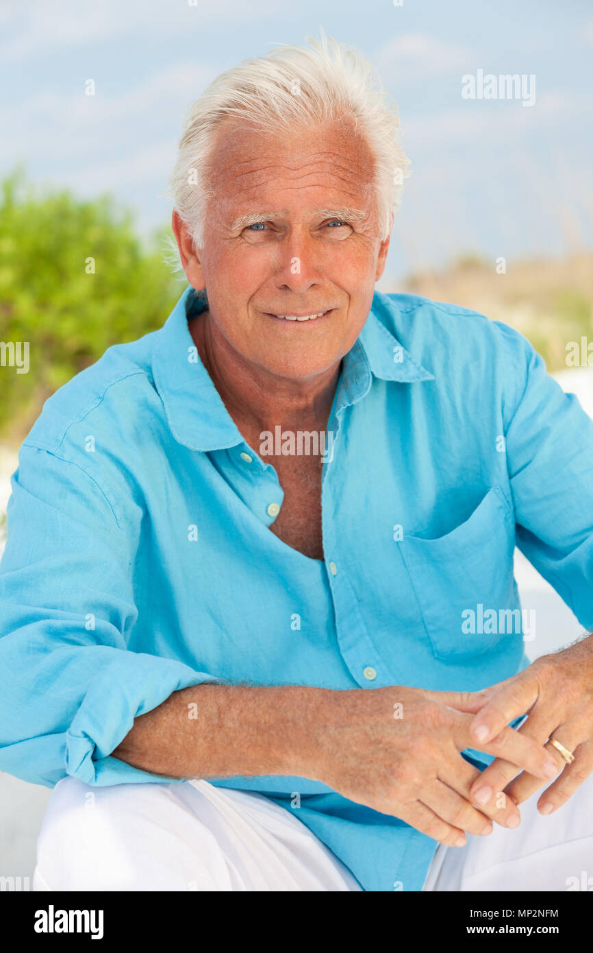 Portrait of a happy handsome man attrayant de s'asseoir à l'extérieur, sur une plage et smiling Banque D'Images