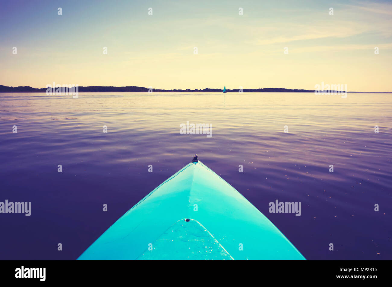 Proue d'un kayak sur un lac au coucher du soleil, toujours dans des tons de couleur photo, selective focus. Banque D'Images Proue d'un kayak sur un lac au coucher du soleil, toujours dans des tons de couleur photo, selective focus. Banque D'Images
