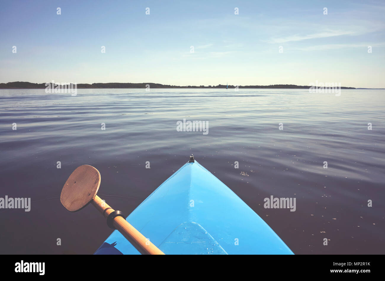 Proue d'un kayak avec pagaie sur un lac encore, aux tons de couleur photo, selective focus. Banque D'Images