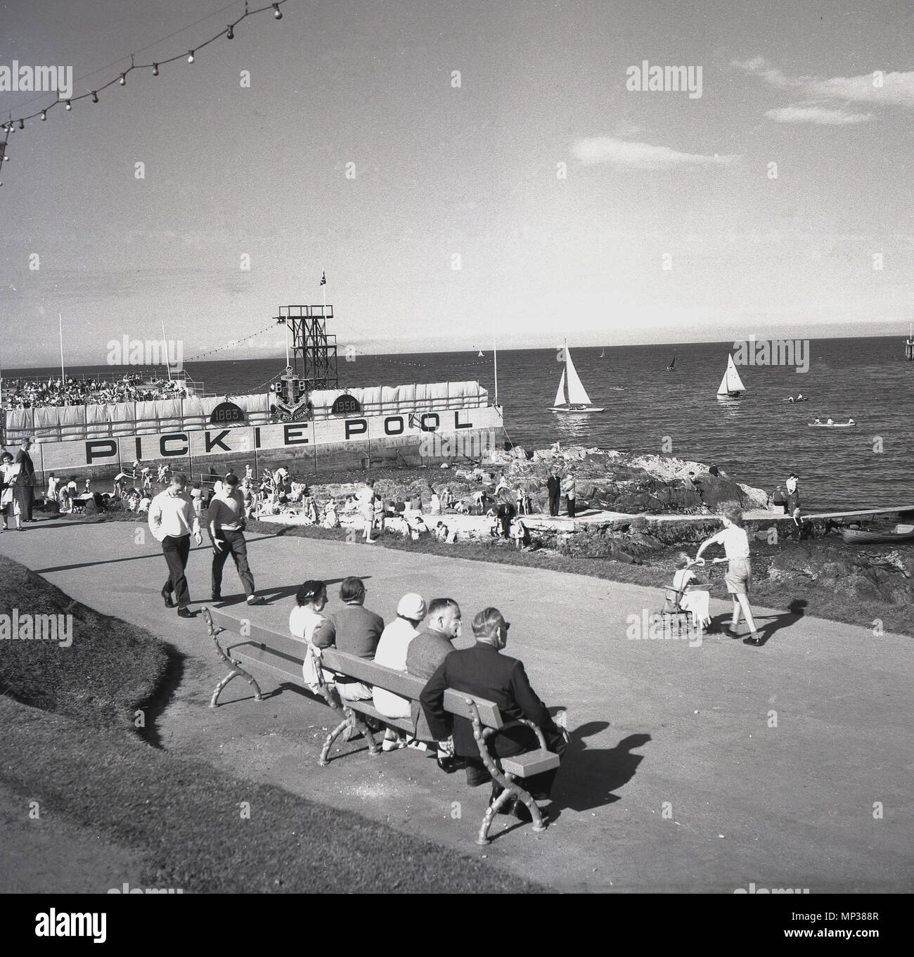 Années 1950, historique, Bangor Seafront, Co. Down, Irlande du Nord. La photo montre les gens sur la promenade de la côte et la piscine Pickie, une piscine extérieure d'eau de mer, qui a ouvert en 1931. Avec un plongeoir de 35 pieds, la piscine a vu des compétitions régulières de plongée et de natation y ont lieu, malgré l'eau froide. La piscine a été démolie à la fin des années 1980. Banque D'Images