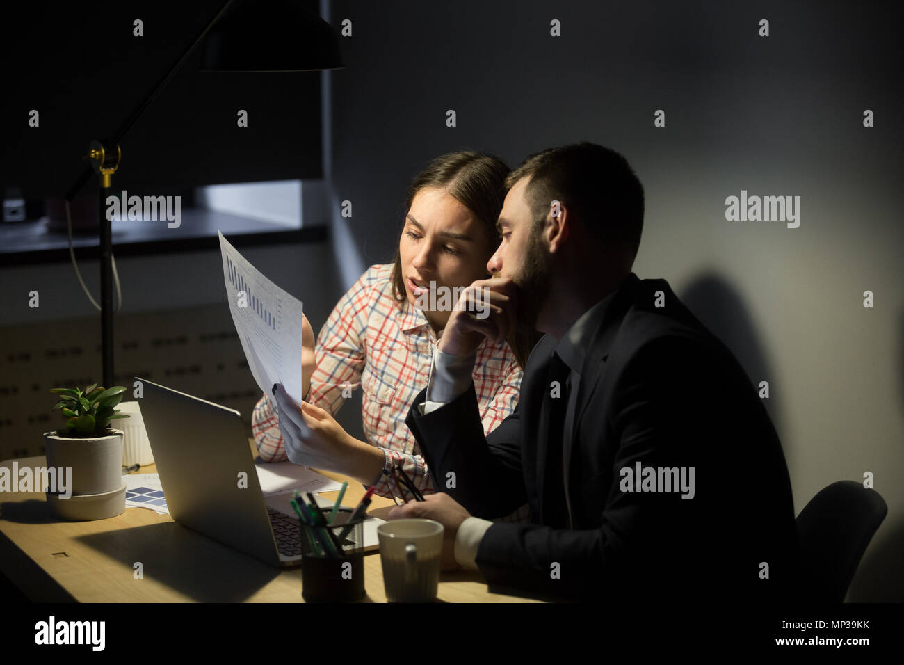 Travailleur féminin expliquant les graphiques pour un collègue masculin Banque D'Images