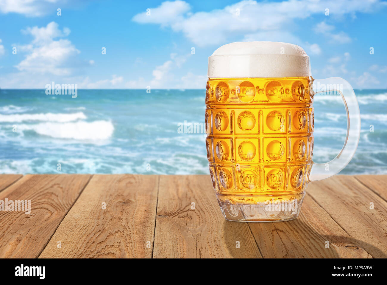 Chope de bière légère de mousse et de bulles sur table en bois contre la mer. Concept de repos et les vacances d'été Banque D'Images