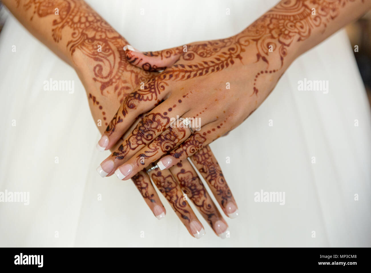 Mehandi bride's mains contre robe de mariée blanche Banque D'Images