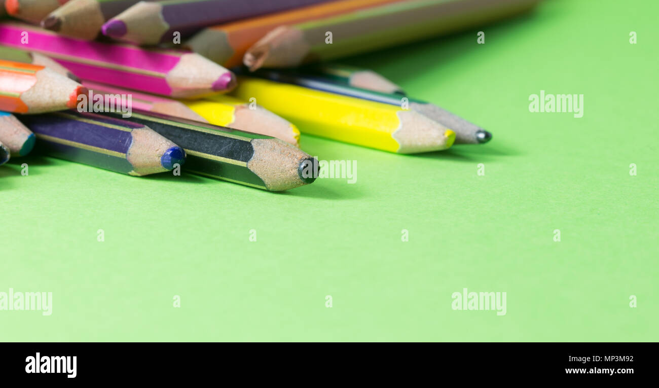 Très utilisé des crayons de couleurs différentes isolé sur un fond vert. Concept de pièces pour acheter de nouveaux Banque D'Images