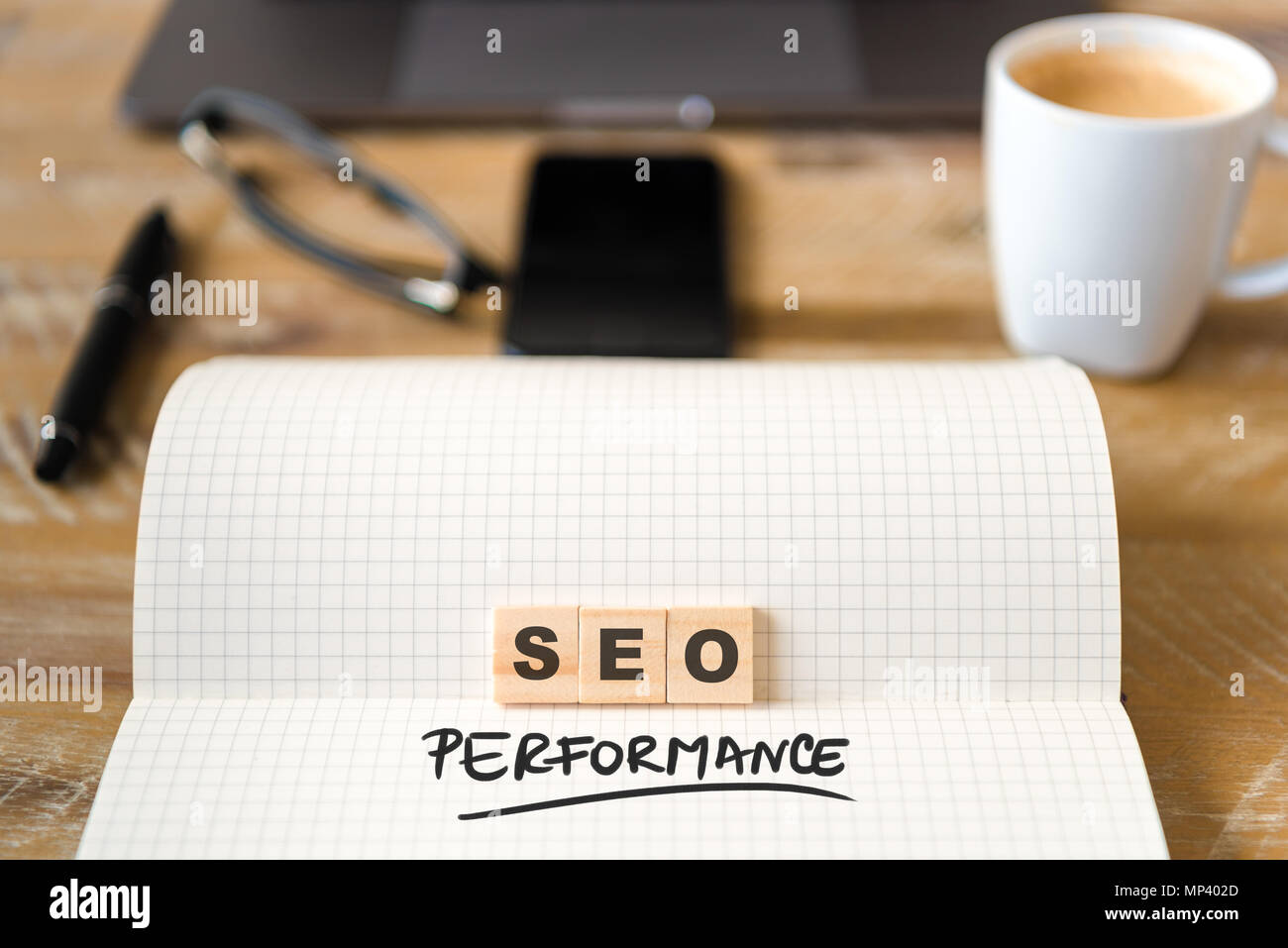 Gros plan sur ordinateur portable sur la table de bois, l'arrière-plan l'accent sur des pièces en bois avec des lettres formant des performances SEO texte. Concept d'image. Banque D'Images