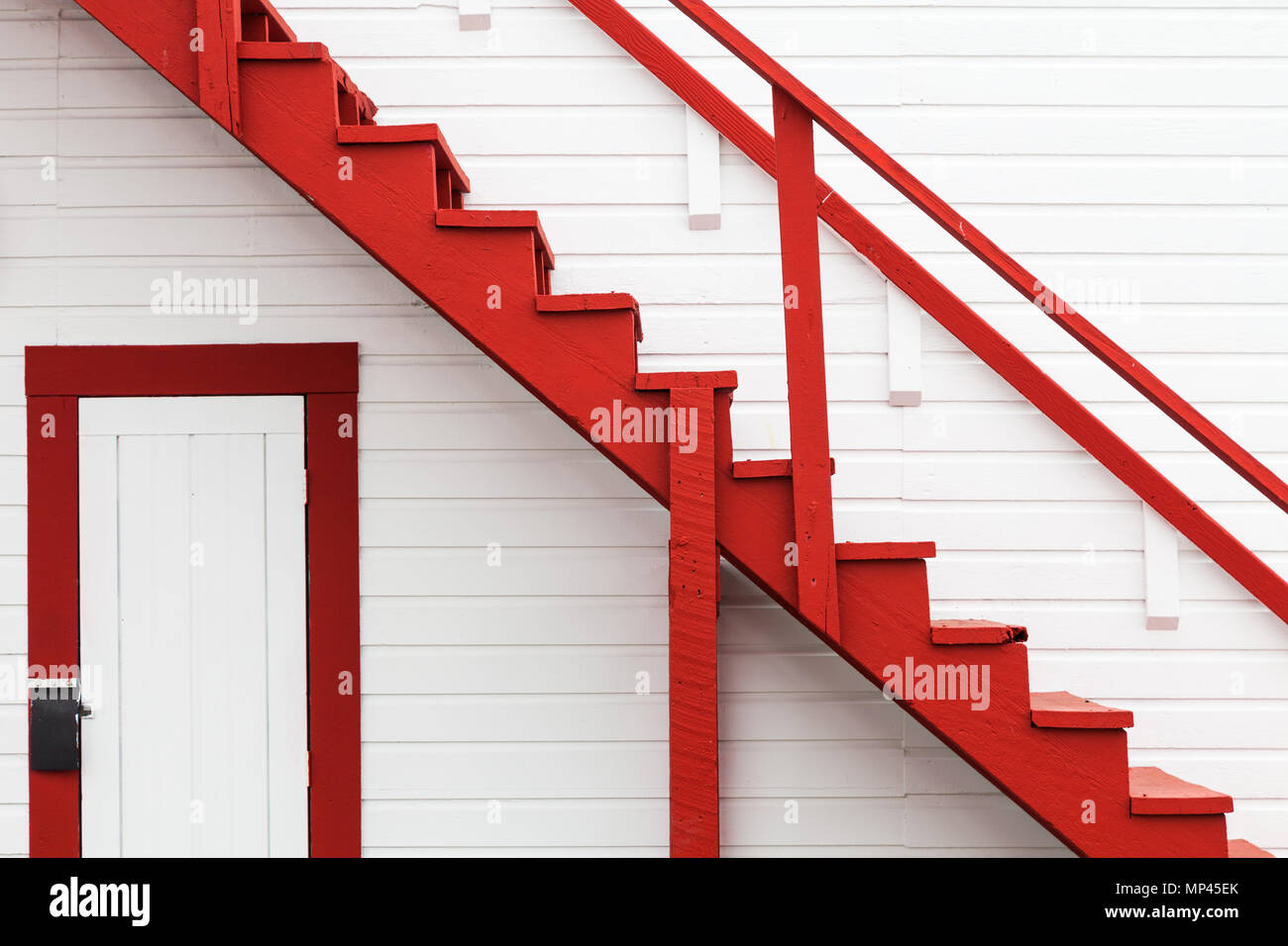 Image abstraite d'un escalier rouge contre un mur blanc Banque D'Images