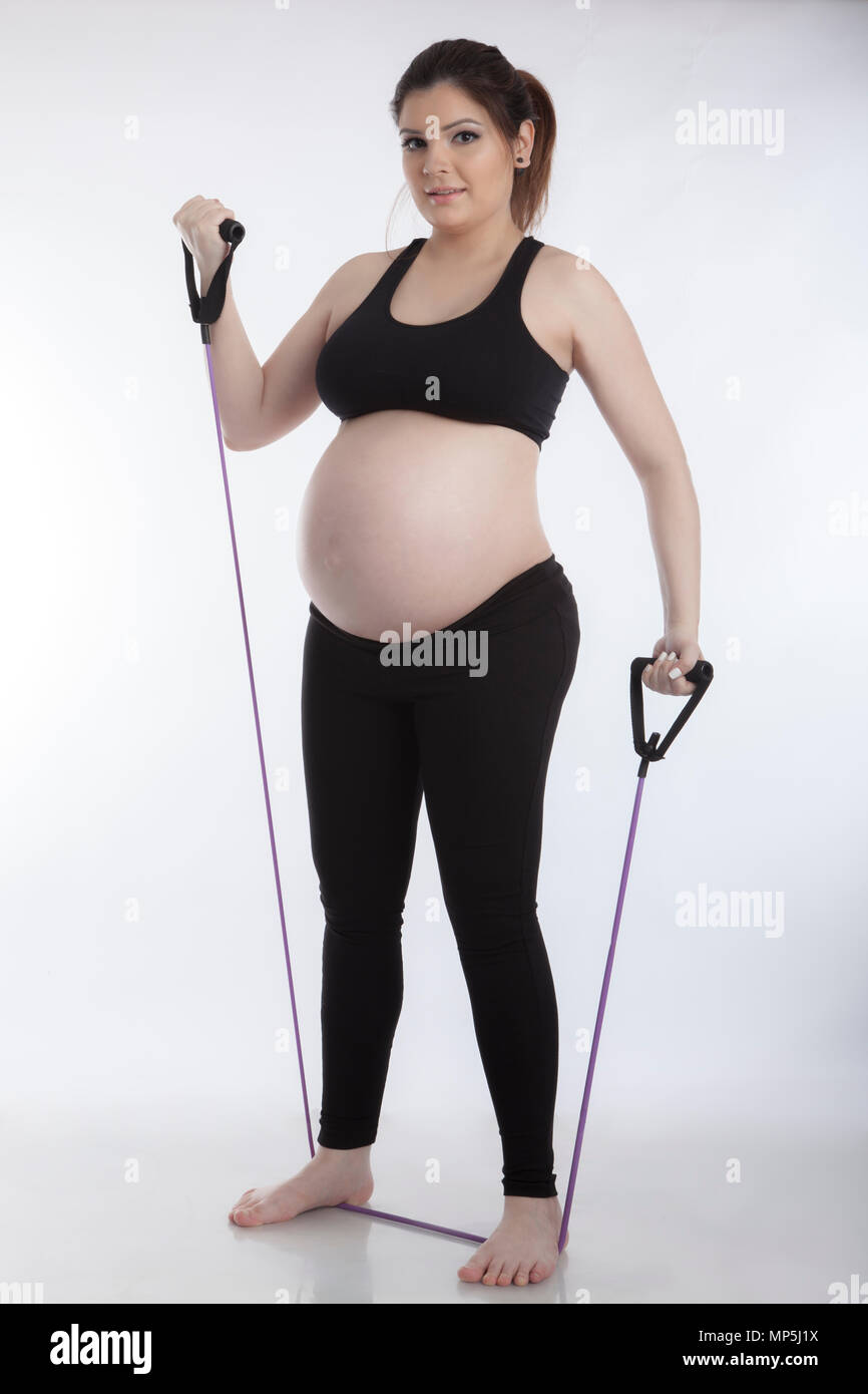 Femme enceinte faisant des exercices de gymnastique sur fond blanc Banque D'Images
