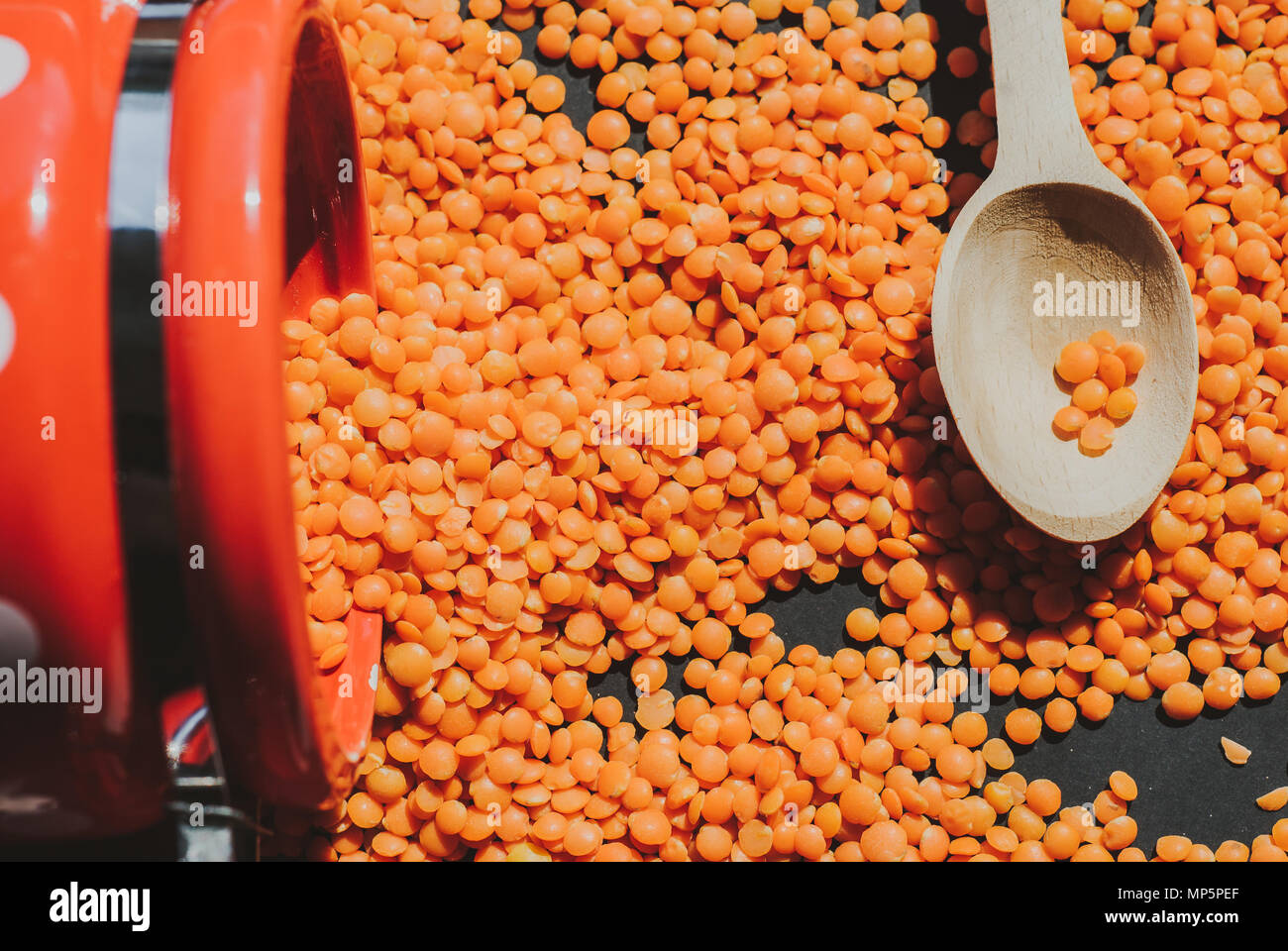 Les lentilles rouges en cuillère en bois composition sur fond noir Banque D'Images