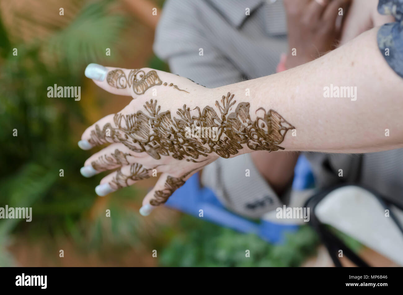 Un artiste à l'henné Shilparamam arts and crafts village, Hyderabad, Inde, l'application de pâte mehndi sur les mains d'une femme touriste. L'art et la diversité. Banque D'Images