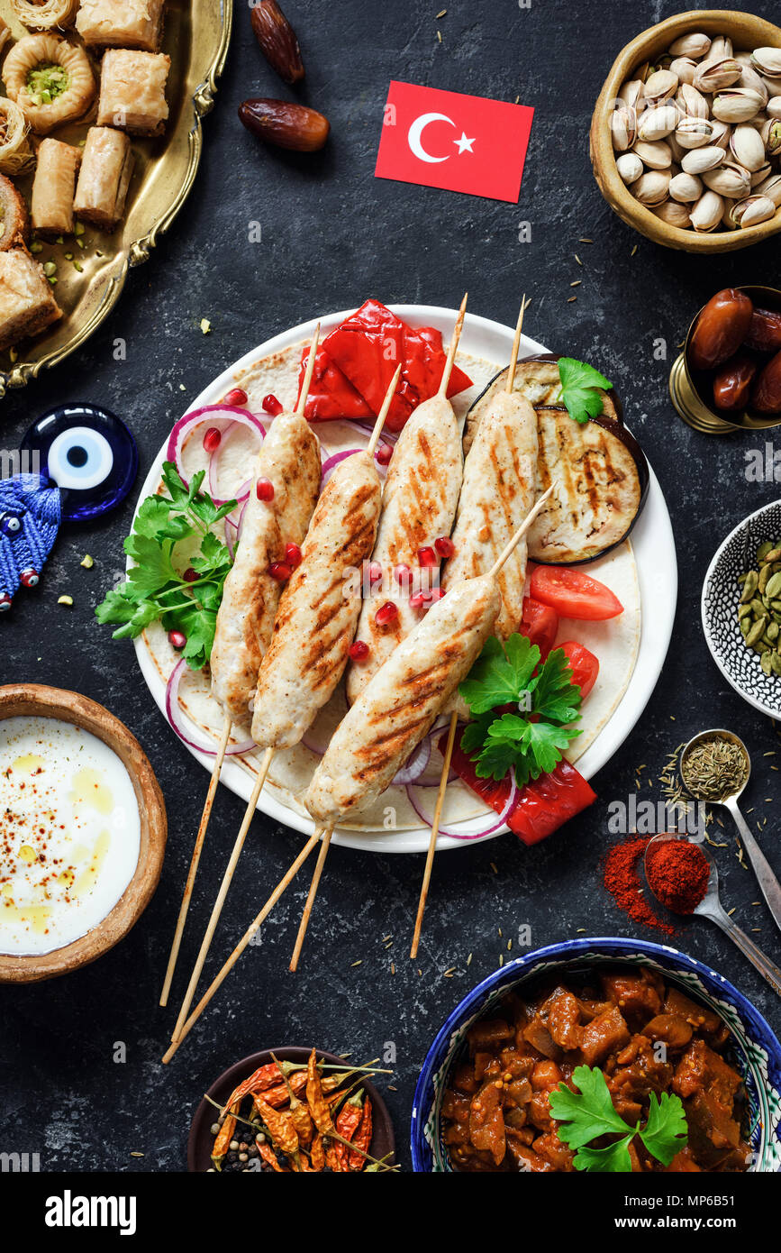 Kebab turc traditionnel ou de viande, bain turc, des bonbons et des légumes grillés, sauce au yogourt. La nourriture turque, drapeau turc sur fond sombre. Vue de dessus, vert Banque D'Images