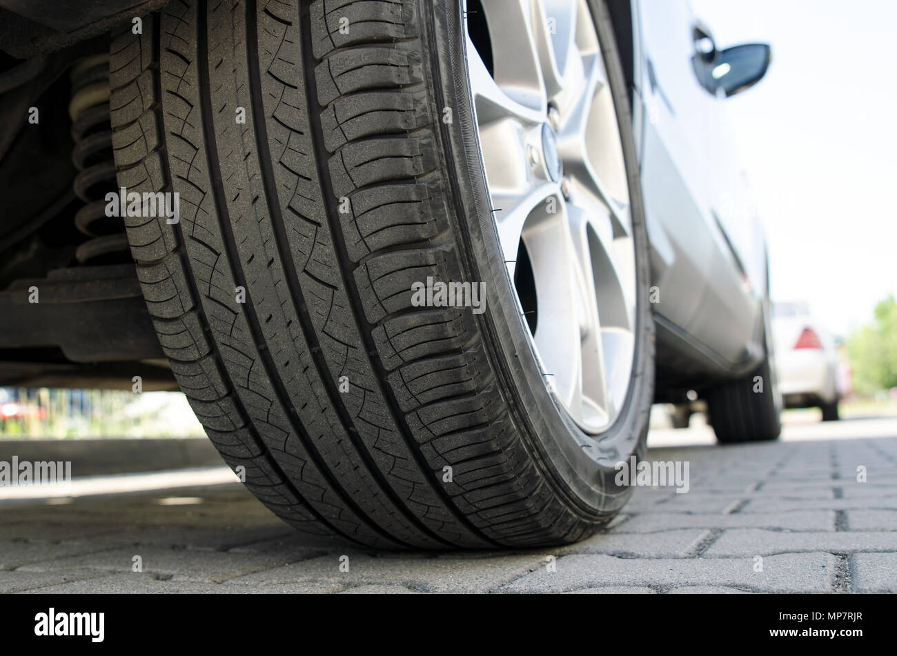 Location de pneu toutes saisons close up, voiture en stationnement. Low angle shot, roue auto avec jante aluminium concept Banque D'Images