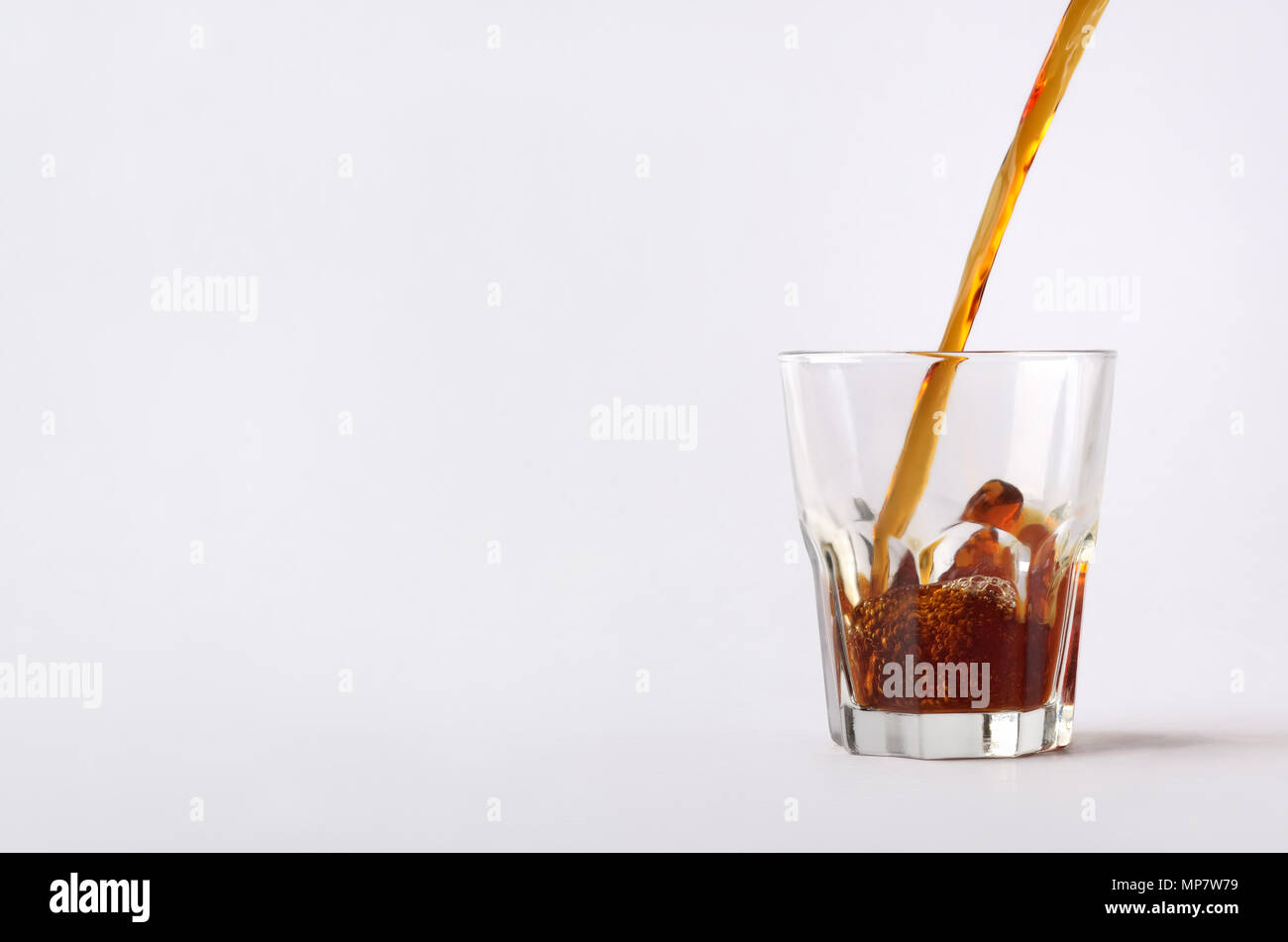 Le close-up composition avec le flux dynamique de café chaud boisson est versé sur la tasse en verre.Image isolé sur le fond blanc. Banque D'Images