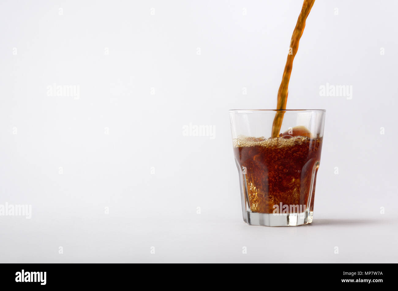 Le close-up composition avec la motion stream de café chaud boire est versé sur la coupe du verre. Droit isolé sur fond blanc le studio. Banque D'Images