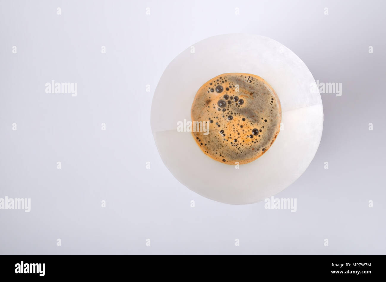 Le filtre en papier avec le mélange de l'eau chaude et le café en poudre dans le verre vintage bouilloire isolé sur le fond blanc. Haut de vue. Banque D'Images