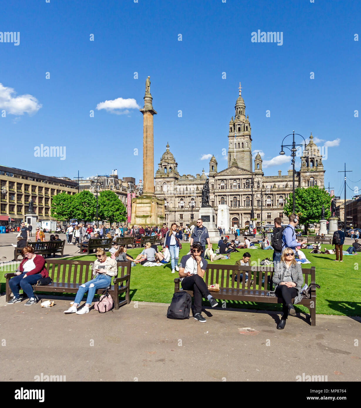 Les personnes bénéficiant de soleil d'été dans la région de George Square dans le centre-ville de Glasgow Ecosse UK avec Sir Walter Scott statue et Glasgow City Chambers Banque D'Images