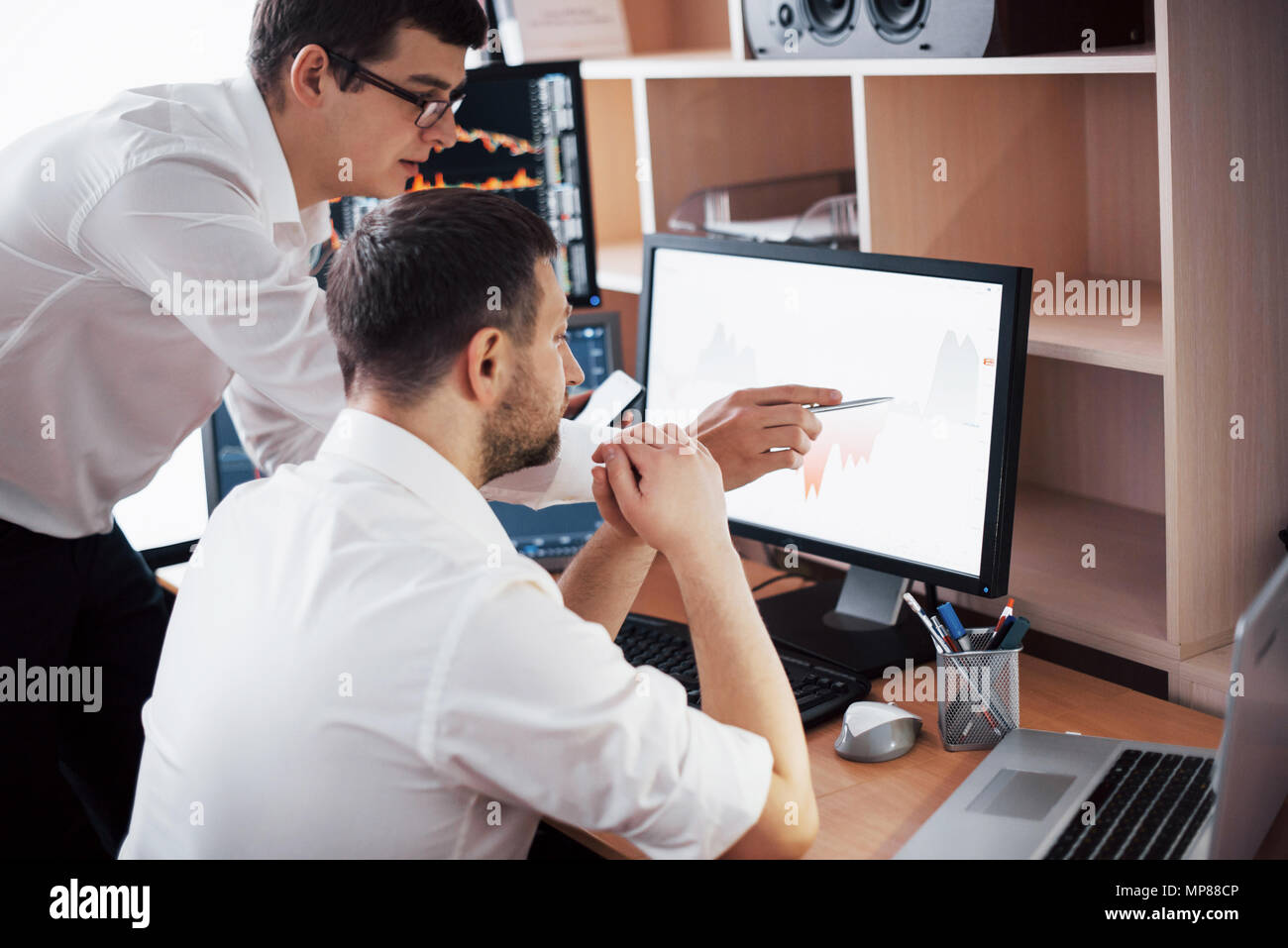 Les stocks commerciaux d'affaires en ligne. Les courtiers en regardant des graphiques, des index et des chiffres sur plusieurs écrans d'ordinateur. Collègues de discussion dans traders bureau. La réussite de l'entreprise concept Banque D'Images