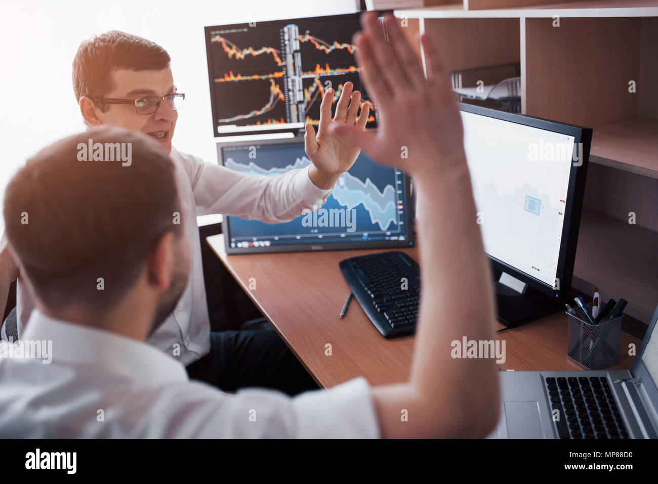 Les stocks commerciaux d'affaires en ligne. Les courtiers en regardant des graphiques, des index et des chiffres sur plusieurs écrans d'ordinateur. Collègues de discussion dans traders bureau. La réussite de l'entreprise concept Banque D'Images