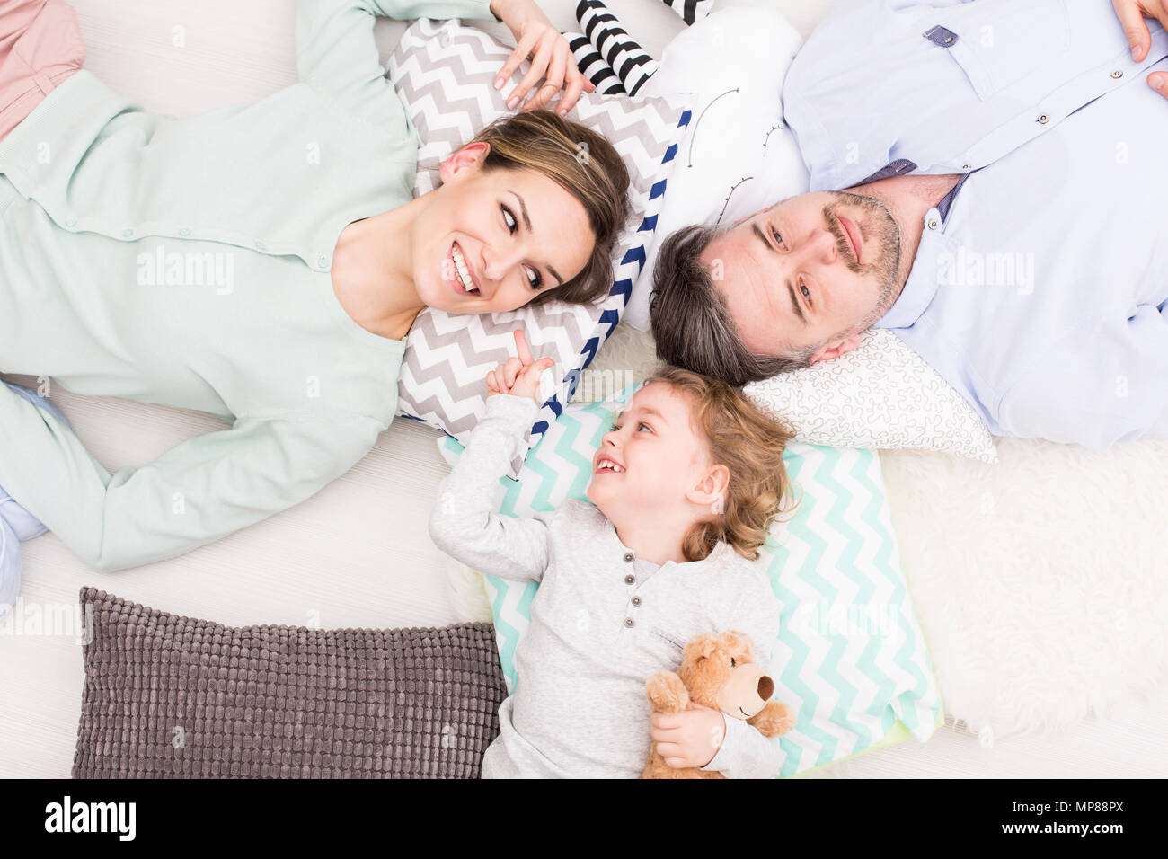 Heureux homme, femme et smiling baby boy lying together in chambre à coucher Banque D'Images