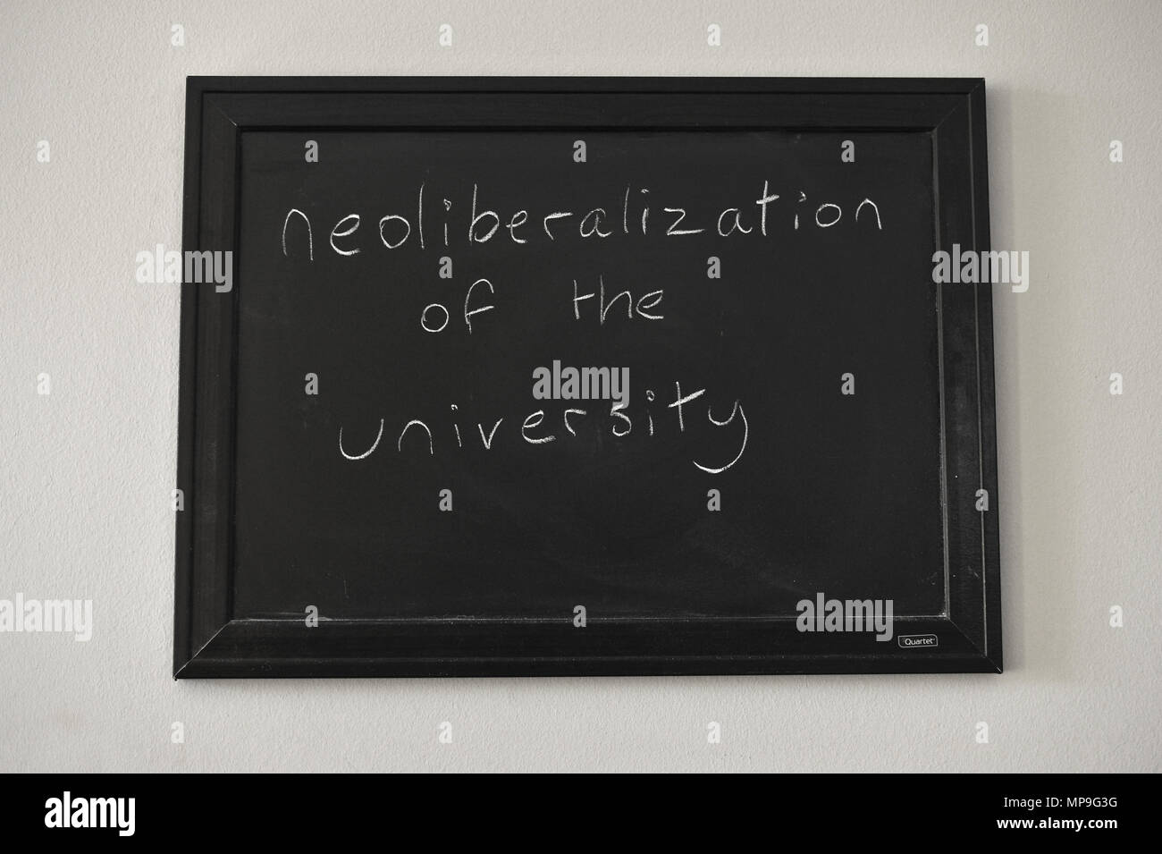 Neoliberalization de l'université écrit en craie blanche sur un tableau noir fixé au mur. Banque D'Images