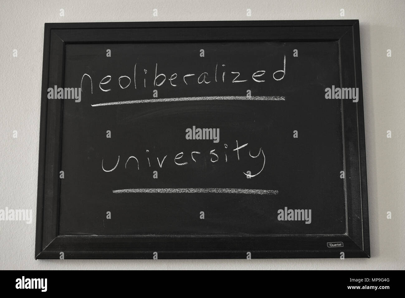 Université Neoliberalized rédigé en craie blanche sur un tableau noir fixé au mur. Banque D'Images