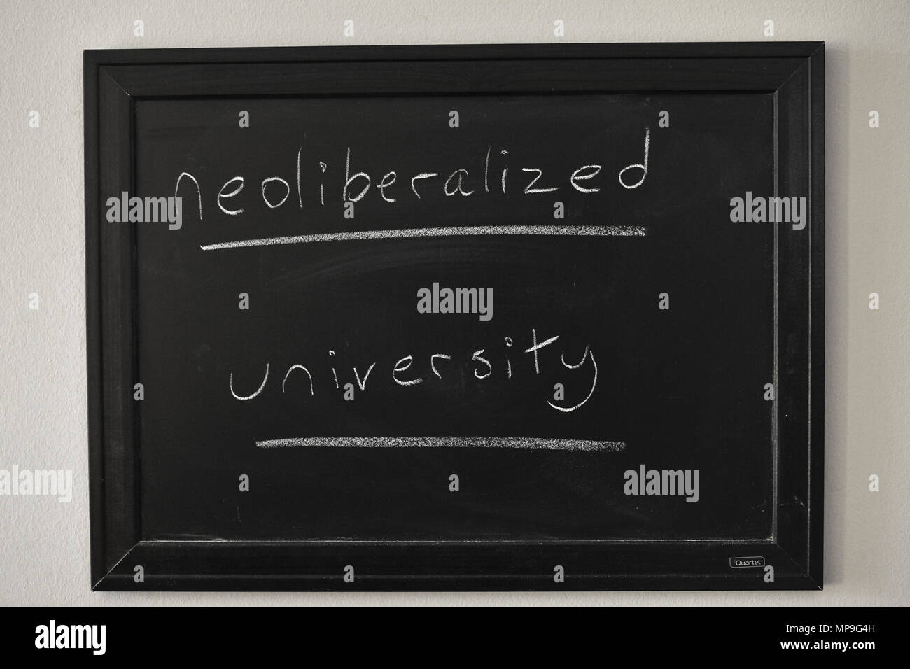 Université Neoliberalized rédigé en craie blanche sur un tableau noir fixé au mur. Banque D'Images