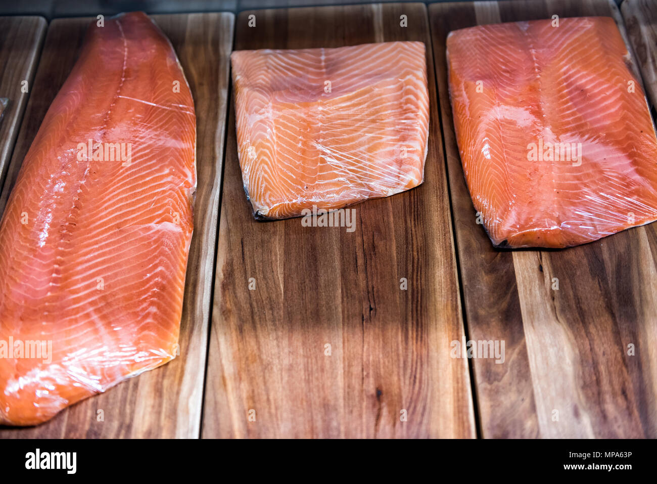 Grand filet de saumon cru fumé coupé sur le stand de fruits de mer shop store sur l'écran enveloppé dans du plastique Banque D'Images