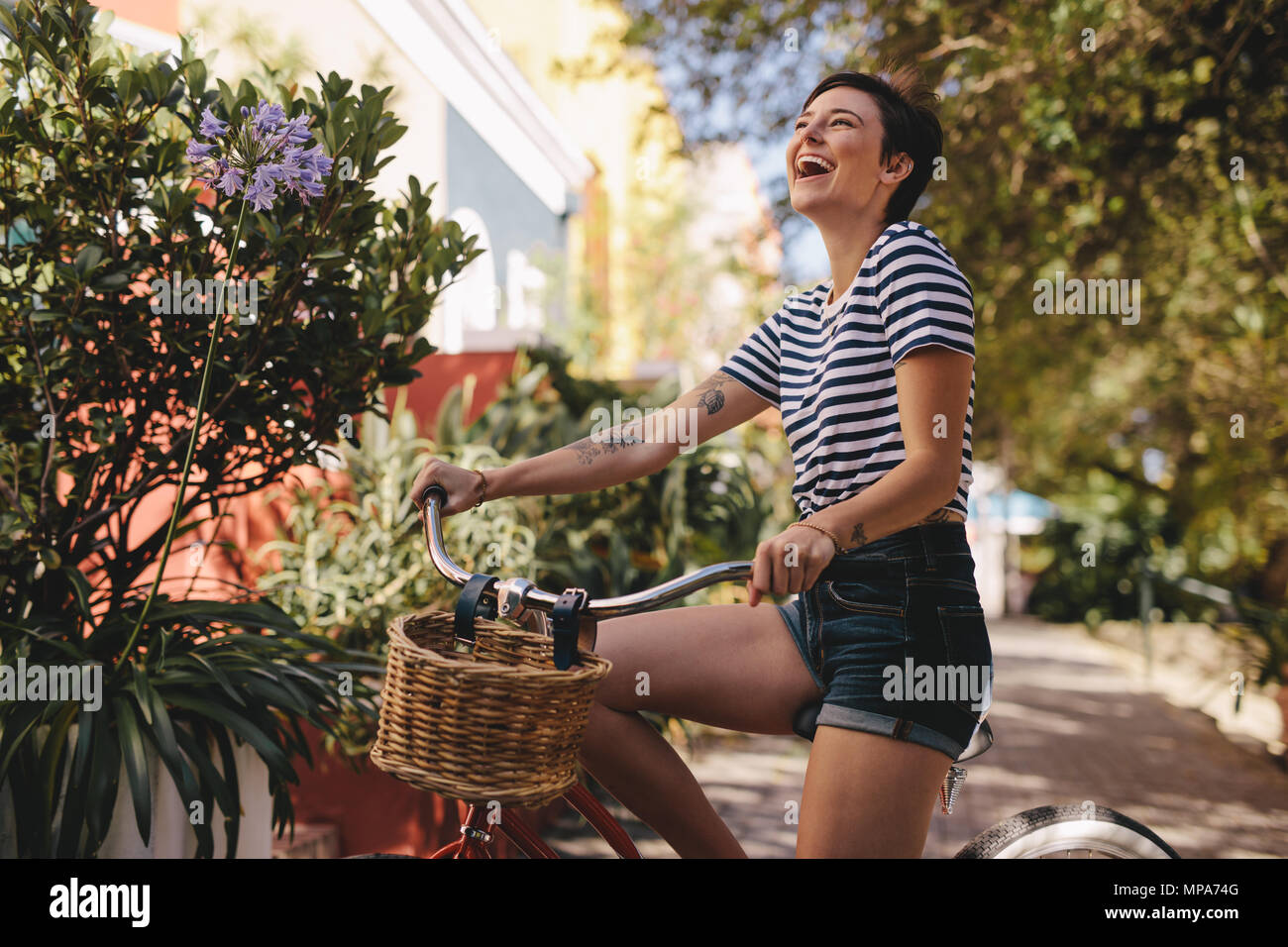 Cheerful woman avec son vélo de rire à l'extérieur. La femme un vélo dans la ville. Banque D'Images