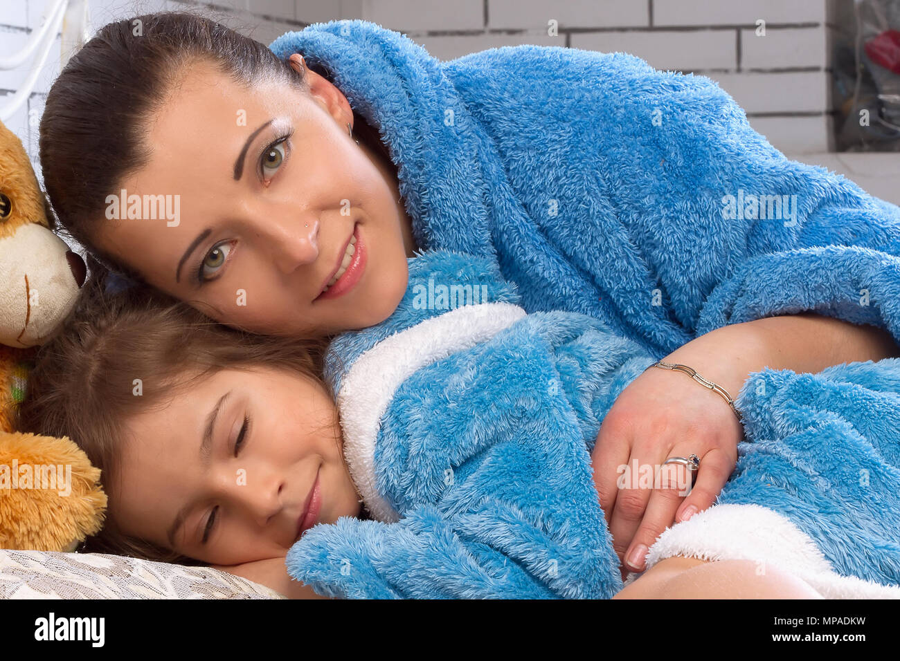 Maman et sa fille dans le même tissu éponge restent au lit Banque D'Images