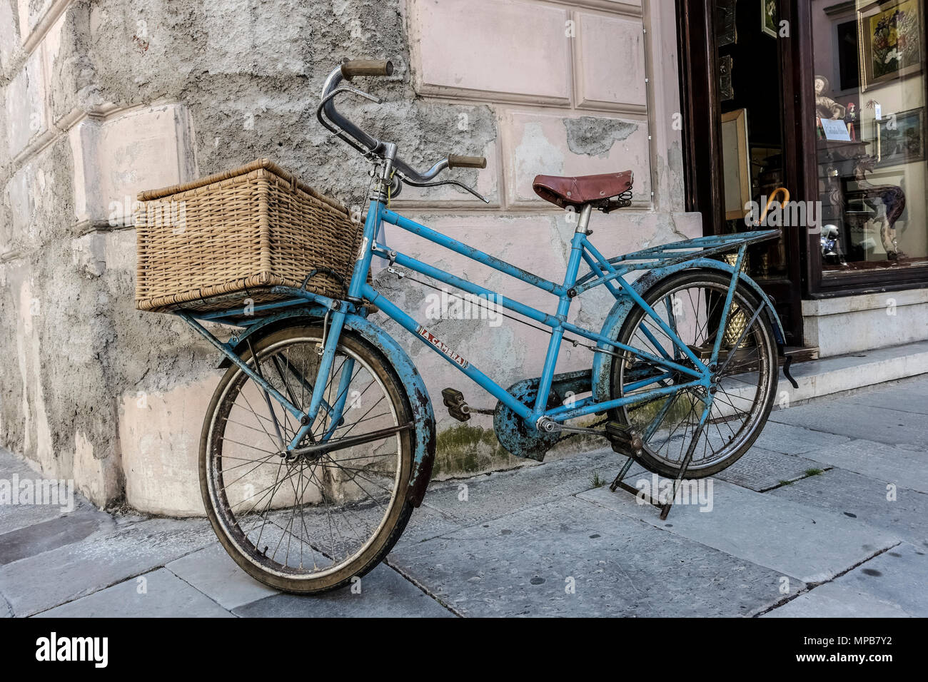Vieux vélo bleu clair avec panier de livraison, garé devant un magasin. Gorizia, Italie, Europe, Union européenne, UE. Banque D'Images