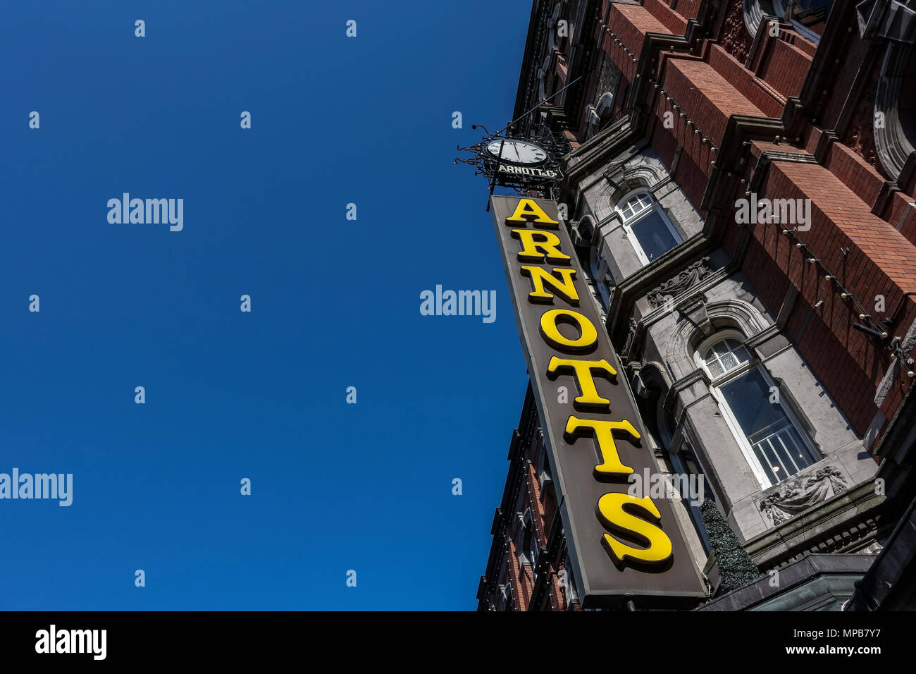 Shopping, panneau du grand magasin d'Arnotts, façade de bâtiment en grès brun, Henry Street, Dublin, Irlande, Europe. Ciel bleu clair, espace de copie, vue à angle bas Banque D'Images