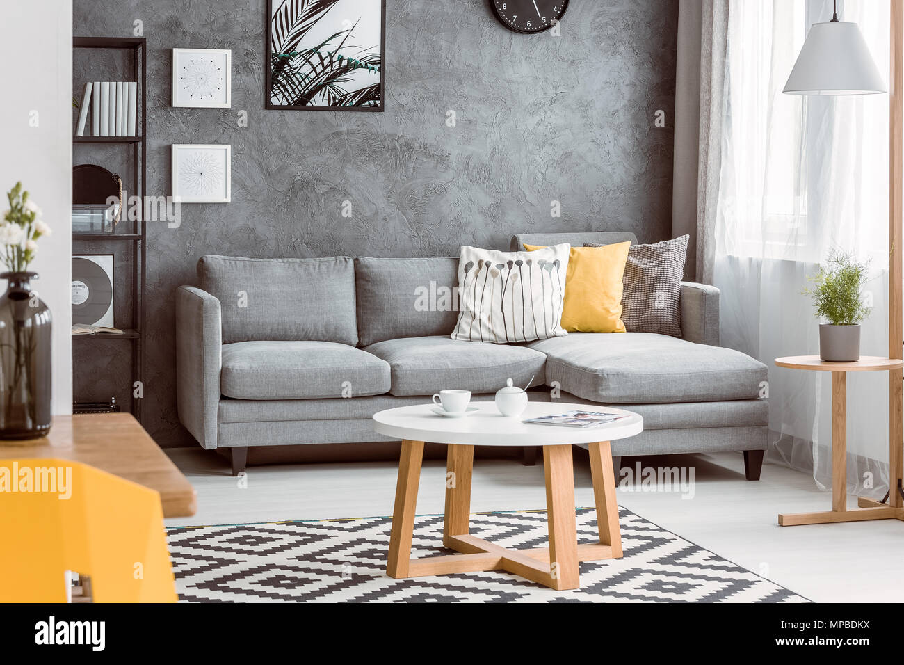 Table basse en bois sur le tapis noir et blanc dans la salle de séjour avec  canapé gris jaune sur l'oreiller Photo Stock - Alamy