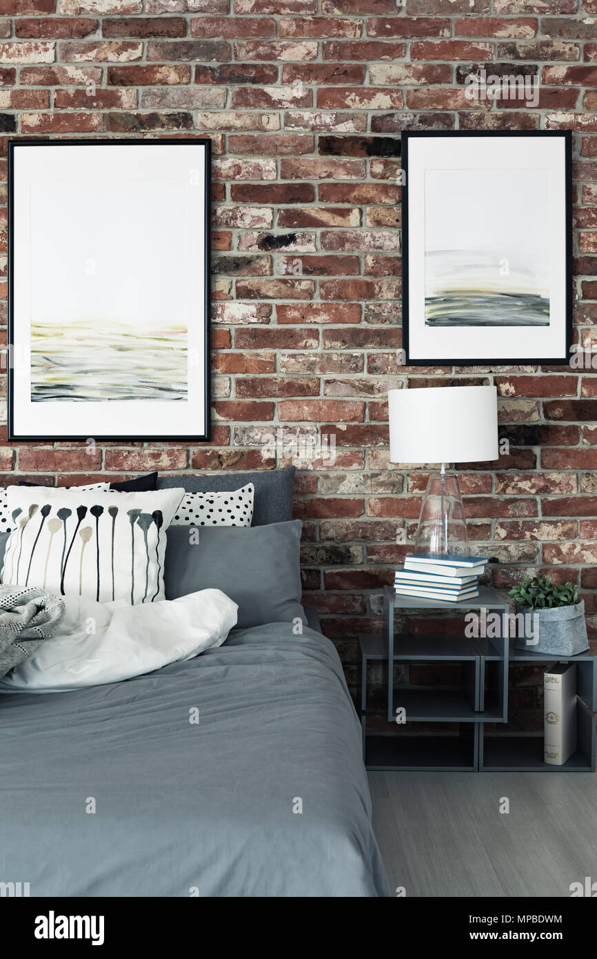 Peintures sur mur de brique au-dessus de l'armoire et lit avec lampe à  l'intérieur chambre à coucher moderne Photo Stock - Alamy