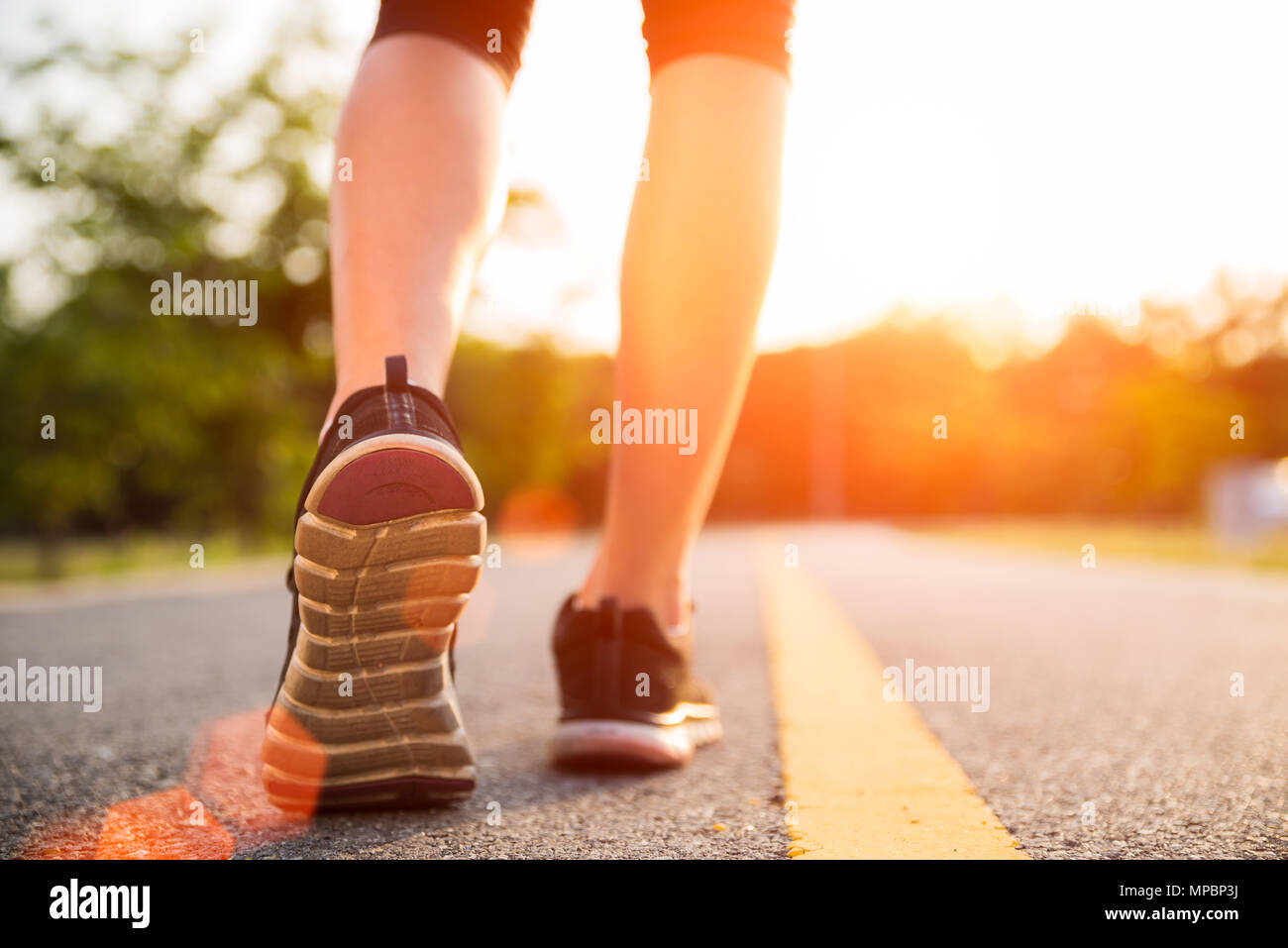 De vie sain femme sport jambes pour courir et marcher tout en exerçant à l'extérieur pendant le lever ou coucher du soleil. Aller de l'avant de la réussite concept. Banque D'Images