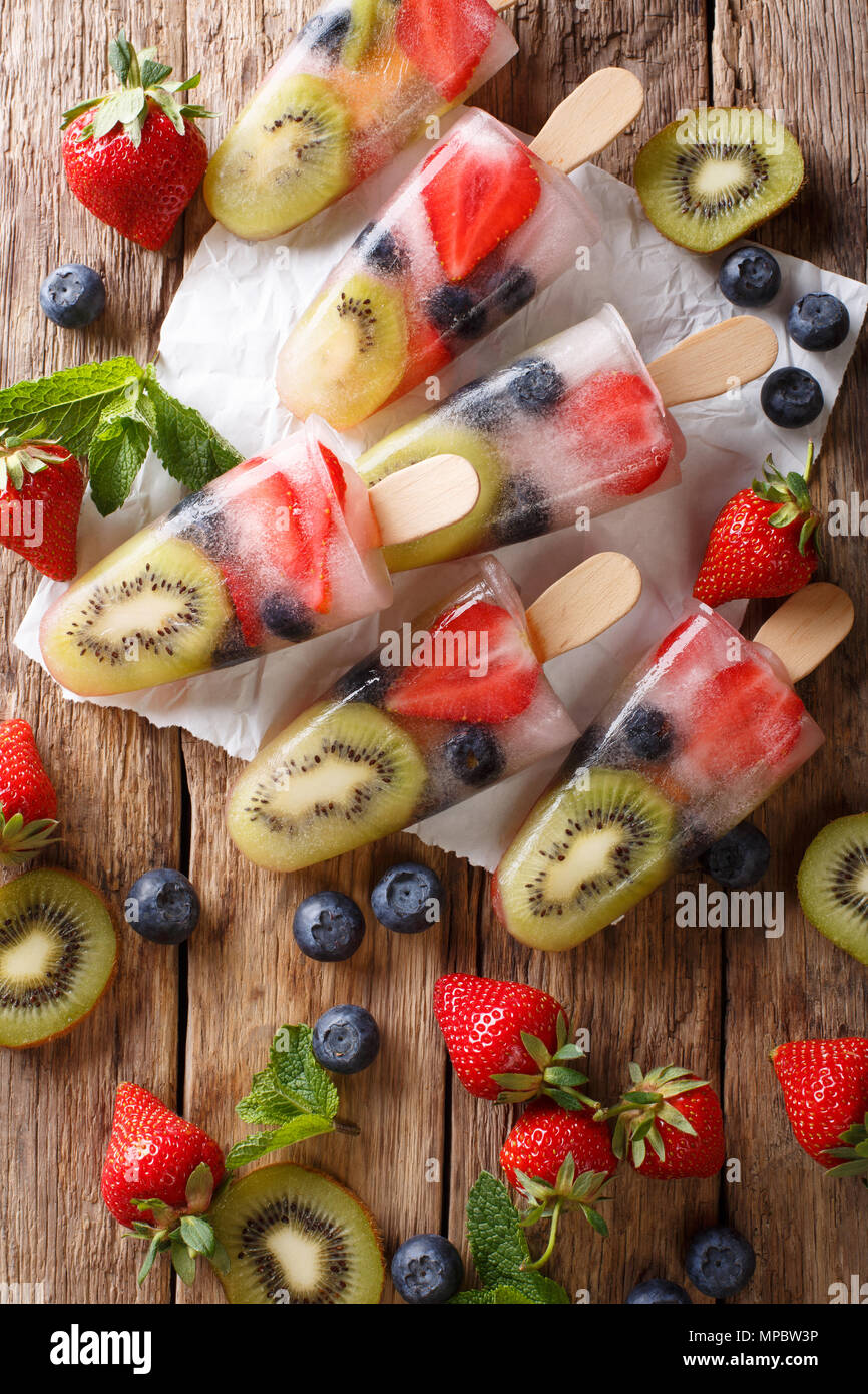 Fruits glacés popsicle rafraîchissant avec des baies, fruits peppermint sur fond de bois macro. Haut Vertical Vue de dessus Banque D'Images