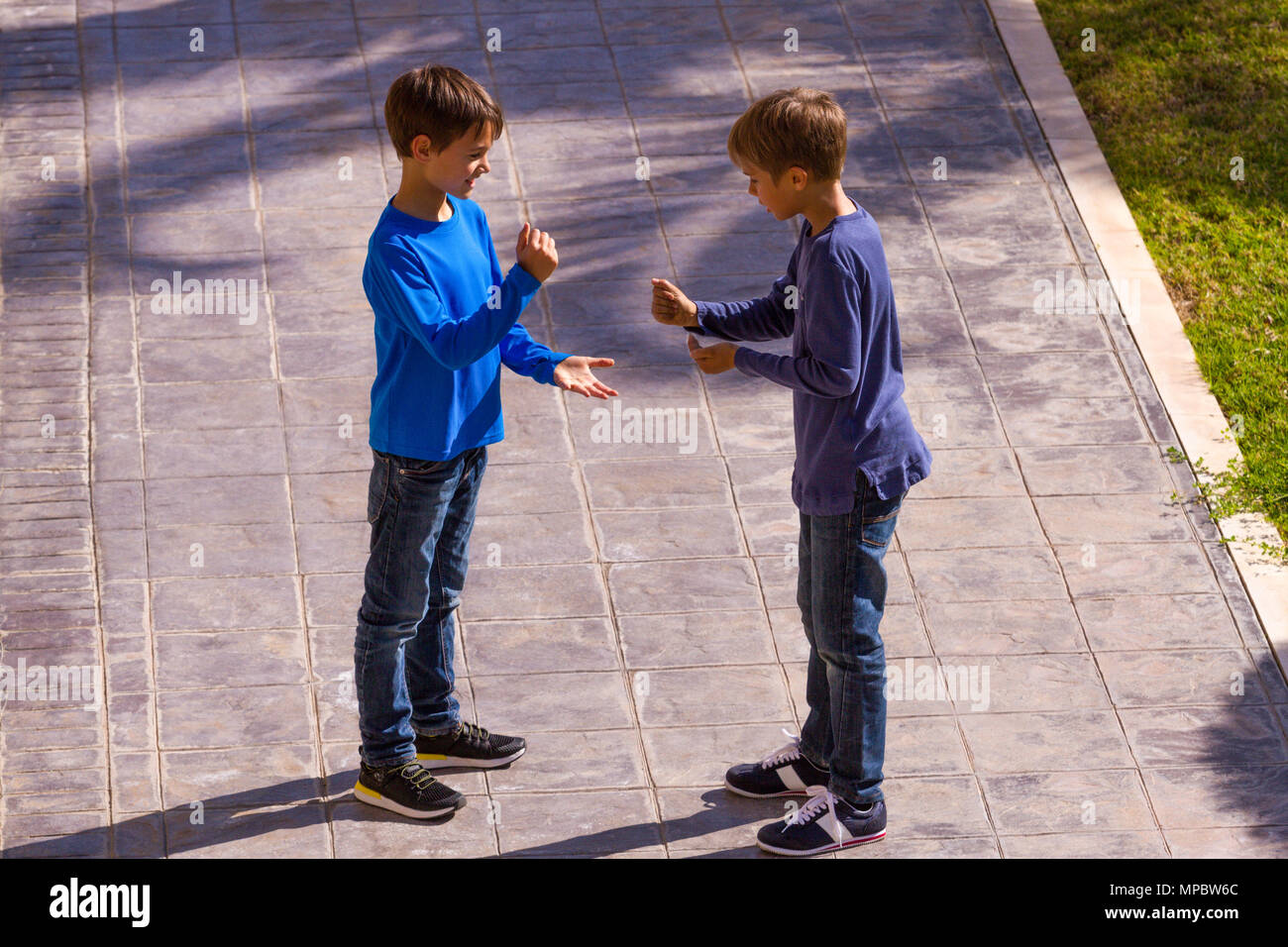 Deux jeunes garçons jouent au jeu Roche-Papier-Ciseaux en plein air Banque D'Images