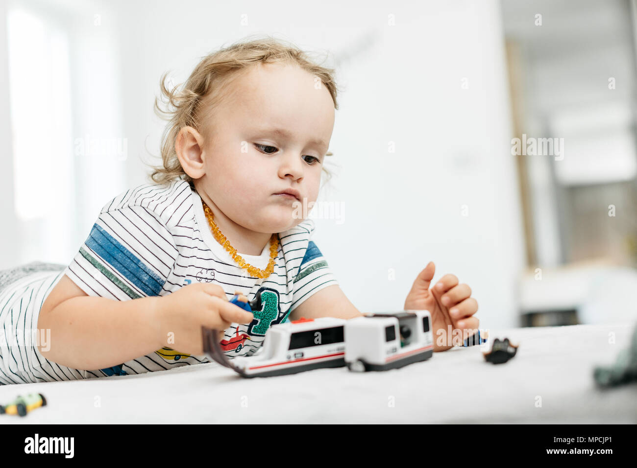Un jeune garçon jouant avec des jouets de sa propre à la maison. Un enfant en jouant avec lui-même par les véhicules en bois. Banque D'Images
