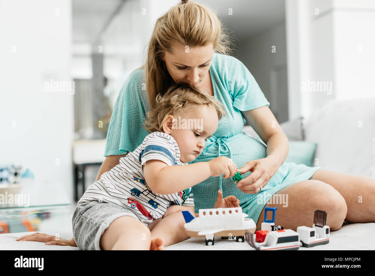 Des moments tendres entre une mère et son enfant en jouant avec des jouets. Le portrait d'une femme enceinte et son bébé garçon jouant avec des jouets en bois. Banque D'Images