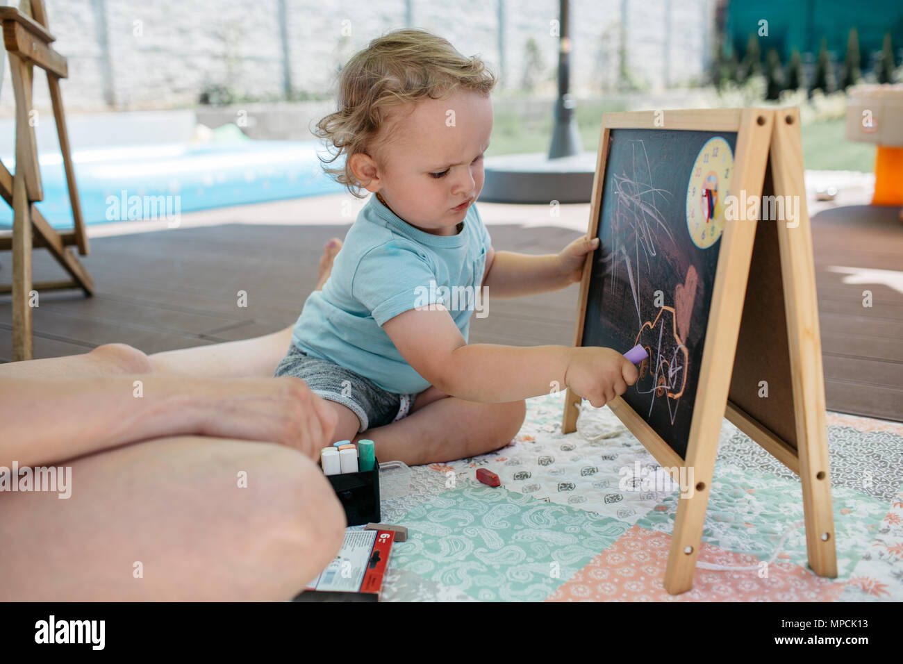 Un bambin s'amuser en s'appuyant sur un tableau. Un petit garçon gribouillis avec une craie sur un tableau. Banque D'Images