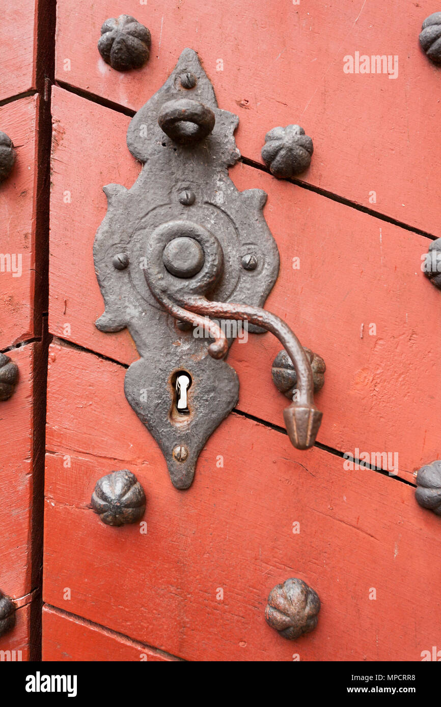 Ancienne serrure rouillée et bouton de porte à Kronborg Slot : Une vieille serrure rouillée et la poignée sur une porte rouge orange en bois renforcé avec grand rivets de fer. Banque D'Images