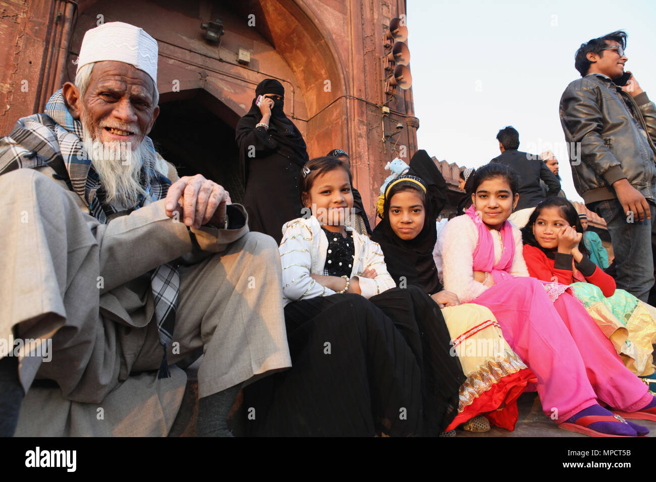 L'Inde, New Delhi, les filles musulmanes et leur grand-père s'asseoir sur les marches de l'entrée de la Jama Masjid dans la vieille ville de Delhi. Banque D'Images