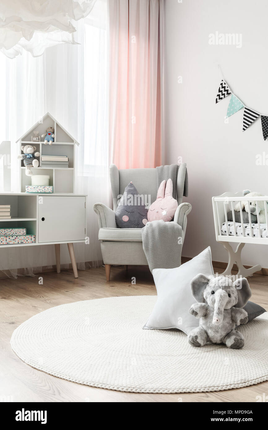 Éléphant gris et star jouet oreiller sur tapis rond blanc dans la chambre  de bébé avec fauteuil gris et placard Photo Stock - Alamy