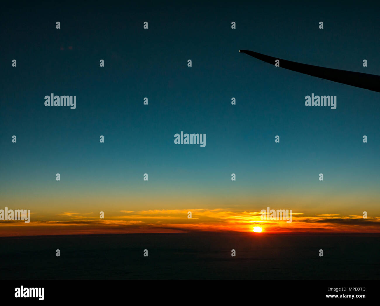 Coucher du soleil orange avec ciel bleu clair et un faible horizon, prises à partir de la fenêtre de l'avion, à l'extrémité de l'aile d'avion silhouette, décoller de Heathro, London, UK Banque D'Images