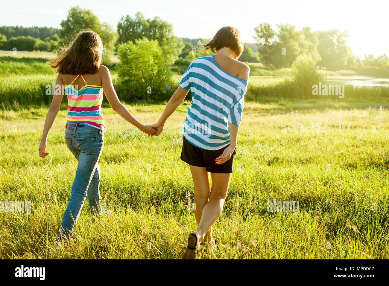 Mère et fille se tenant la main, vue de dos. Photo sur la nature dans un beau jour d'été. Banque D'Images