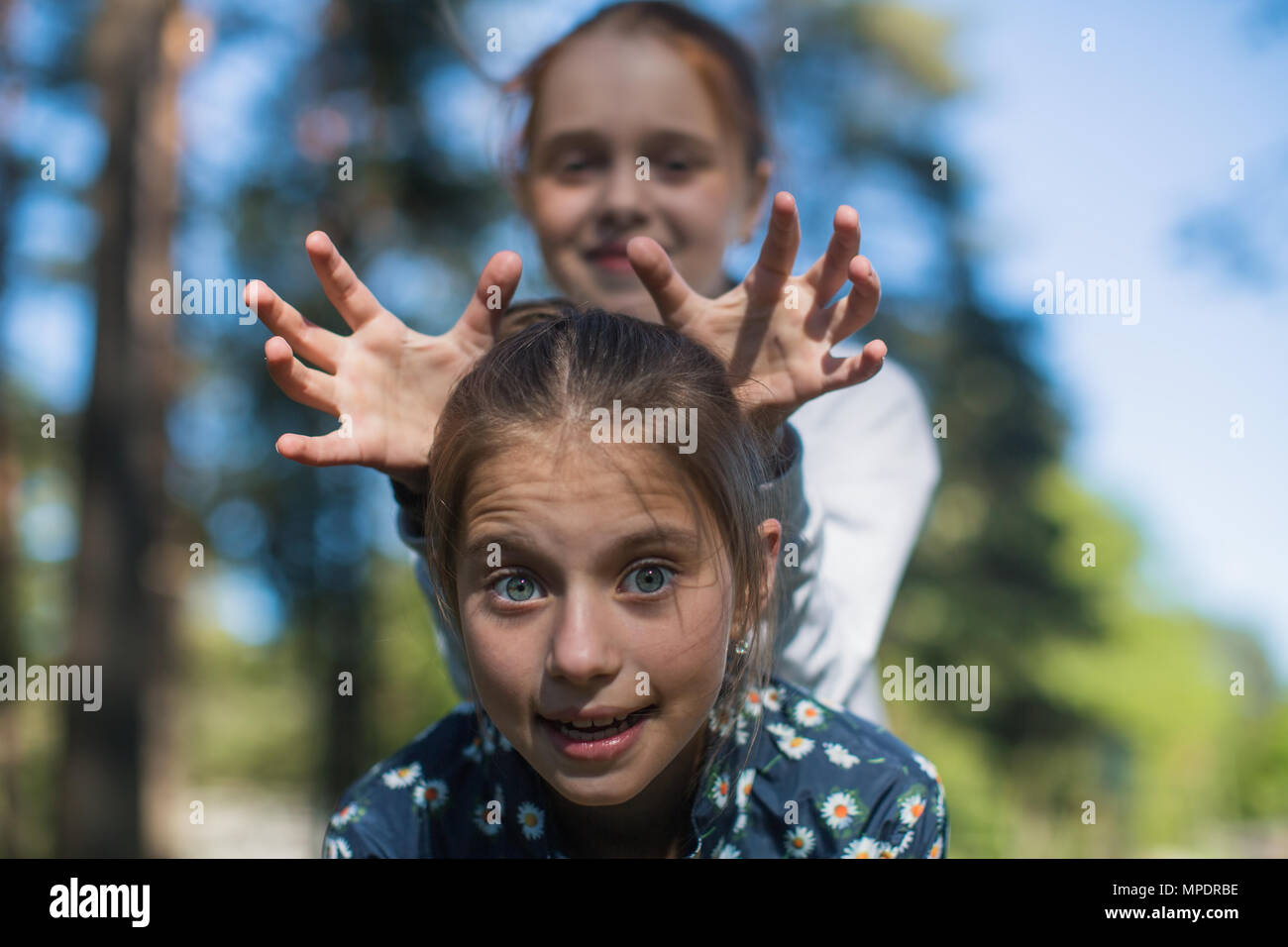 Deux filles soeurs ou amies s'amuser à l'extérieur (ne cerf à partir de mains) Banque D'Images