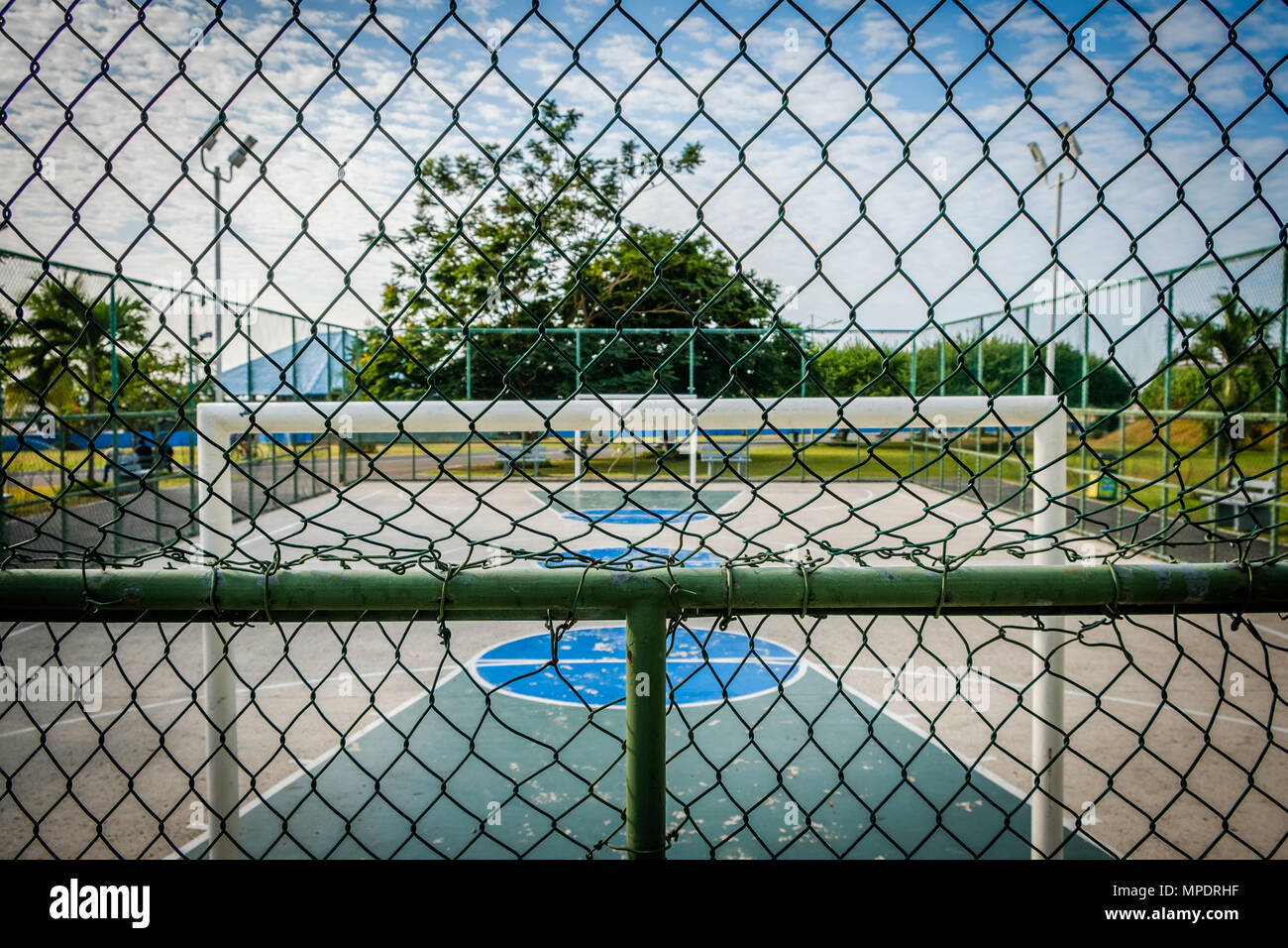 Basket-ball et un terrain de football en parc public derrière fence Banque D'Images