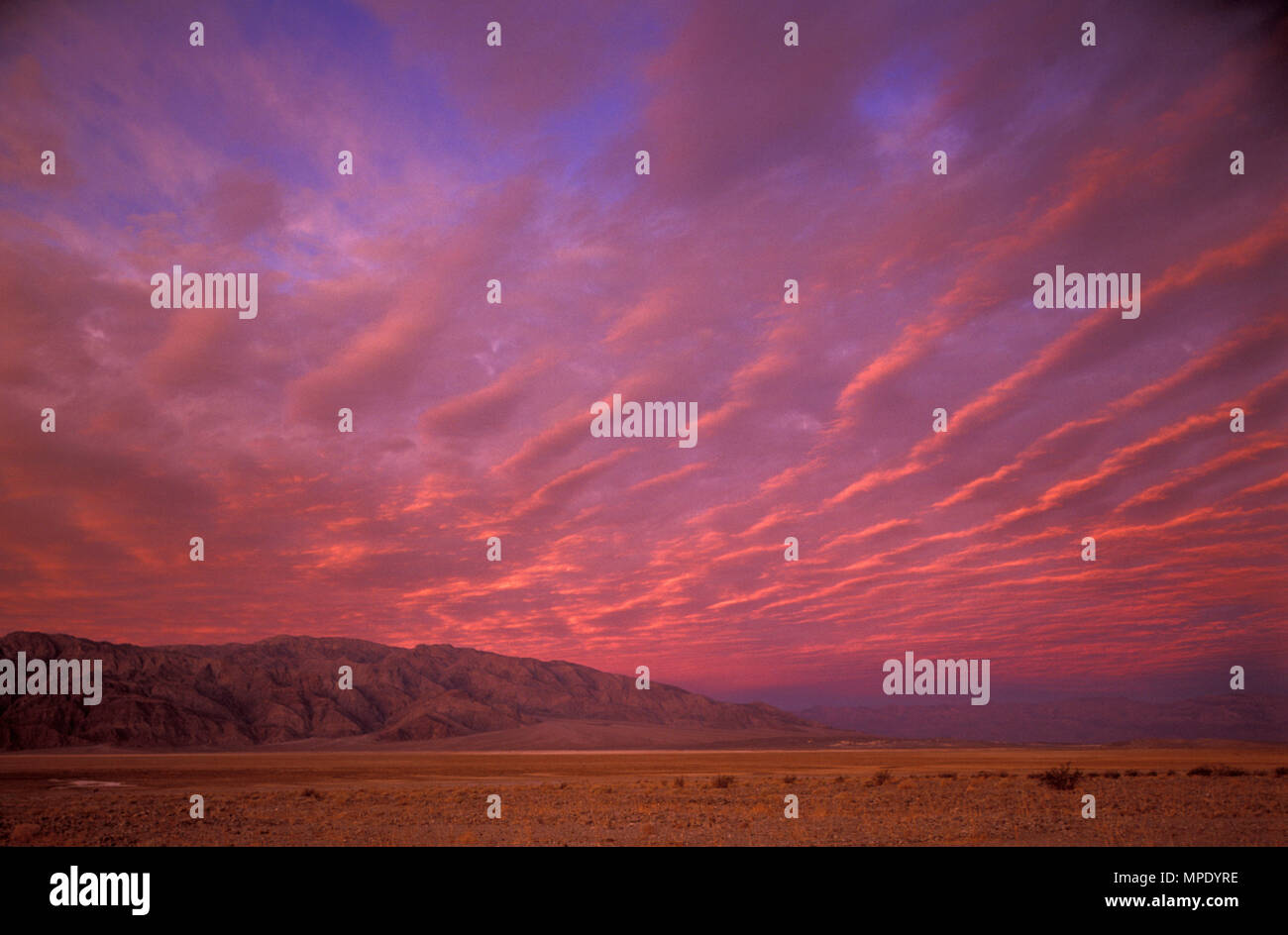 Lever du soleil dans la vallée de la mort, avec des motifs de nuages et de montagnes lointaines, Death Valley, CA, USA Banque D'Images