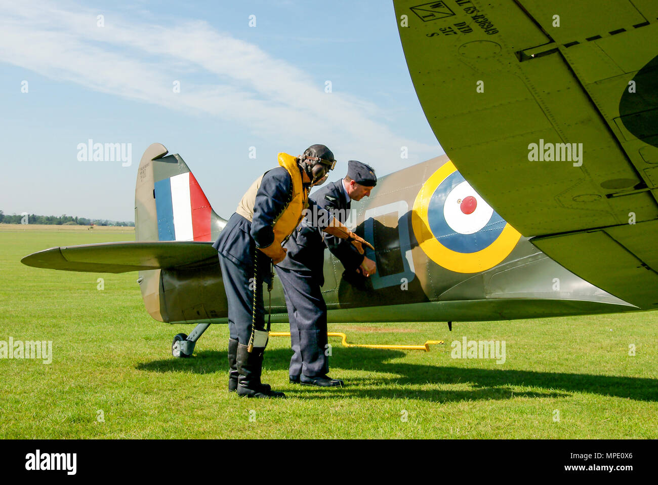 L'ère de la bataille d'Angleterre Spitfire Mk1 avec l'équipe au sol & pilote mécanicien de reconstitution historique discuter les dégâts de combat apparent. Supermarine Spitfire Mark 1 avion Banque D'Images